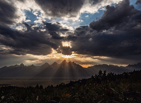 Setting sun burts through clouds over the Teton Mountains, Wyoming