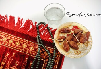 Dates, a glass of water and seeds on the prayer mats. Ramadhan kareem concept. marhaban ya ramadan. 
