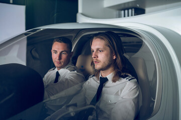 Male pilot guiding trainee in flight simulator