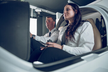 Low angle view of male pilot guiding female trainee in flying flight simulator