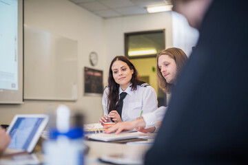 Pilot trainees studying while sitting at desk in classroom