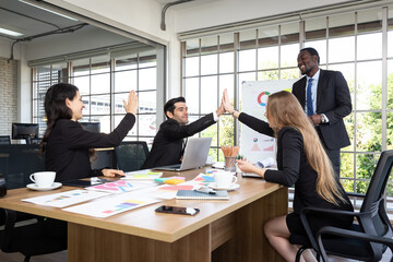 Multiracial euphoric business team give high five at meeting room.