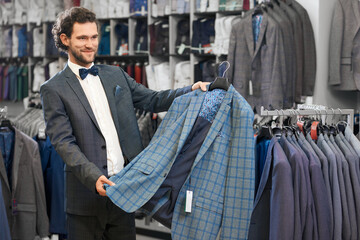 Young man picking up suit in store.