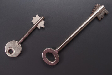 Ein kleiner und ein normalgroßer Tresorschlüssel, Safe-Schlüssel auf einem dunklen Hintergrund