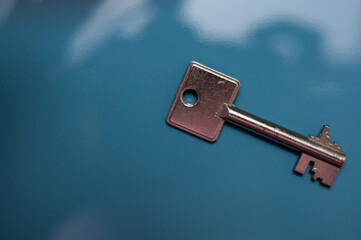 A safe key, safe key in a smaller version against a background with shadow play. Ein Tresorschlüssel, Safe-Schlüssel in kleinerer Ausführung vor einem Hintergrund mit Schattenspiel