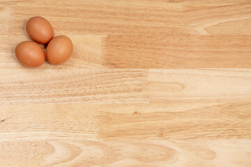 Three eggs on the upper left corner of the wooden table