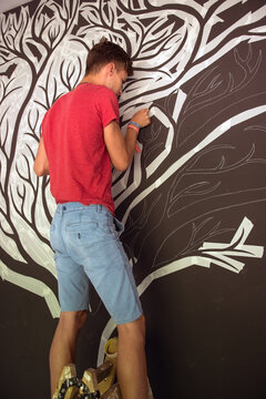 The young man who cuts the branches of a custom tree on the wall