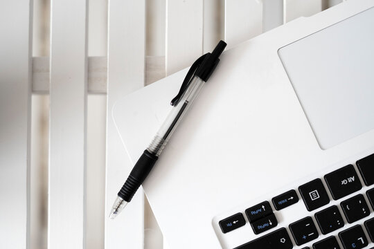Black pen on top of a white laptop.