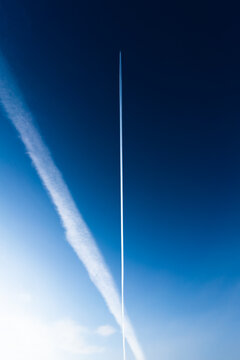 Chem trails from an airplane cross across a blue sky