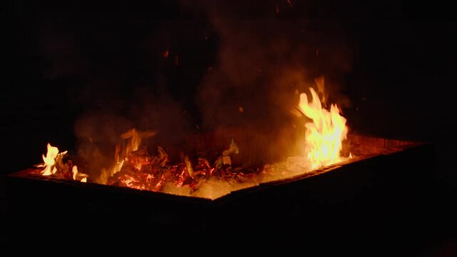 Shot of a fire pit burning trash at night.