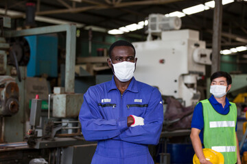 Fototapeta na wymiar Black male engineer and Asian male worker wearing protective medical face mask at work in the industry factory. Group of diversity male worker wearing medical face mask for health in the factory