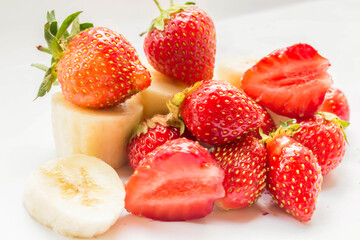 Whole strawberries, half and banana slices are isolated on a white background