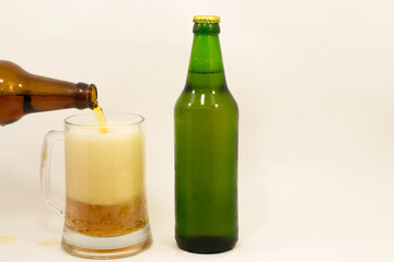 A full beer mug with a bottle on a light background.