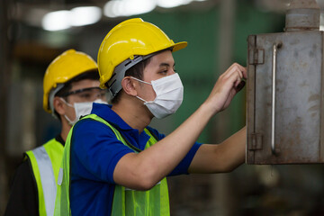 Group of Asian male worker wearing face mask working at factory. Team of Asian male engineer worker checking, repair or maintenance machine in the industry factory. Industry and health care concept