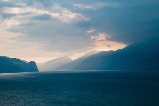 Sunrise light rays shine over mountains onto Lake Garda in Italy