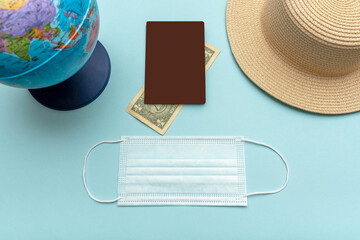Traveling by plane during a pandemic. On a blue background globe, hat, passport, money.