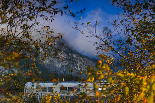 Converted school bus parked at night in front of mountain in Squamish