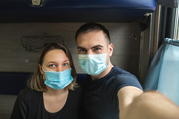 Fototapeta na wymiar Couple in medical masks sitting in the train. Honeymoon, coronavirus travel concept.