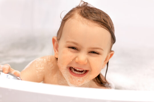 A cute little funny child expression girl laughing to take a bath. Looks into the camera