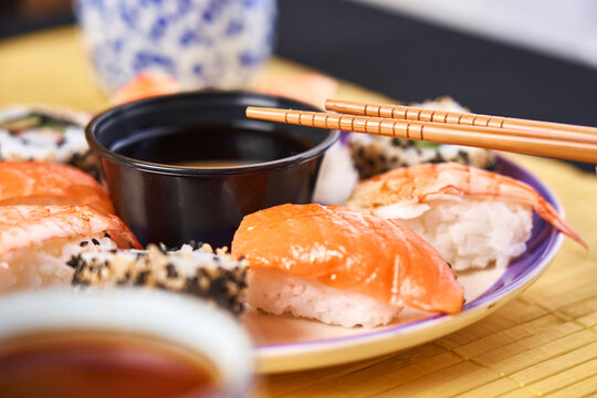 Variety of sushi with wasabi, ginger and bowl of soy sauce on dark gro