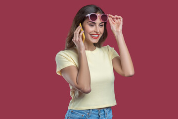 Good looking woman taking off glasses talking on smartphone