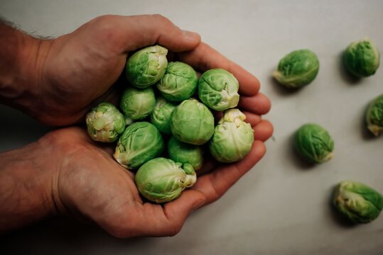 brussel sprouts in chefs hands on chopping board