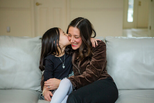 loving mother and daughter hugging on couch at home