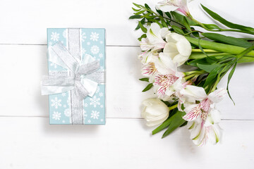 Beautiful spring flowers on white wooden background. Festive floral composition with craft paper gift boxes. Valentine's day, Womans day, mothers day greeting card . Top view flat lay