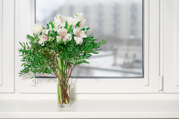 bouquet of decorative white lilies in a vase on the window