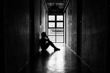 Lonely young man feeling depressed and stressed sitting in the dark walkway, Negative emotion and mental health concept
