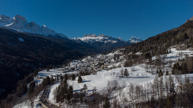 Aerial drone view of valley around Cortina d'Ampezzo, looking from the village of Volo di Cadore towards the snowy hills in february on a sunny day. © Anze