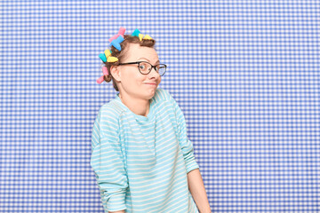 Portrait of funny cheerful girl with colorful hair curlers on head
