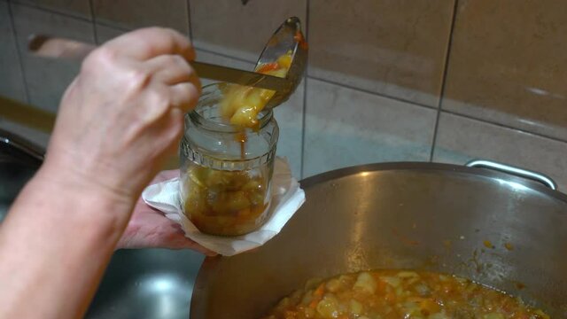 Pouring homemade mixed vegetable (G&uuml;ve&ccedil;) into sterile jars - (4K)
