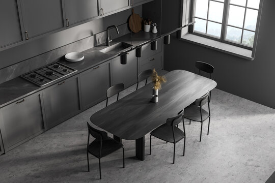 Top view of dark grey kitchen with black eating table and chairs near window
