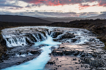 Summer sunset view of Bruarfoss - Brúarárfoss Waterfall, secluded spot with cascading blue waters in Iceland Europe, part of the famous golden circle route