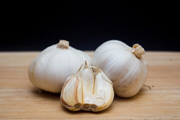 The garlics isolated black background on a wooden cutting board
