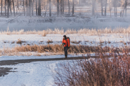 Photographer walking on bike path next to frozen river in Calgary