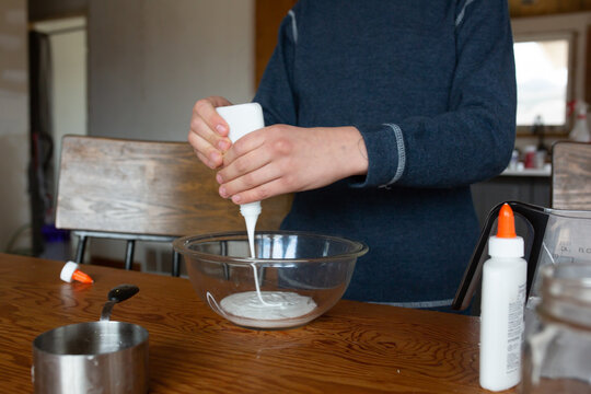 Boy pouring glue into bowl to make slime