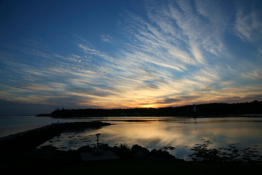 A summer sunrise along the coast of Maine showing white clouds and blu