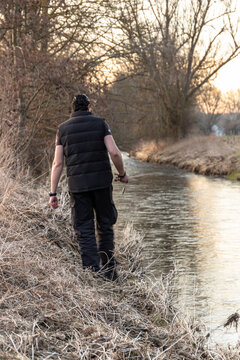 Fisherman walking alongside the river searching for a good spot