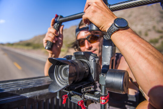 Videographer filming with Gimbal stabilizer from back of truck