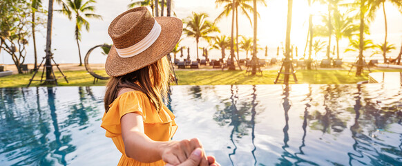 Young couple traveler relaxing and enjoying the sunset by a tropical resort pool while traveling...