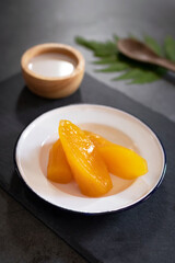 Sweet potato or Yam in syrup usually served coconut milk in vintage zinc coating dish on black stone background. Traditional desserts in Thailand.