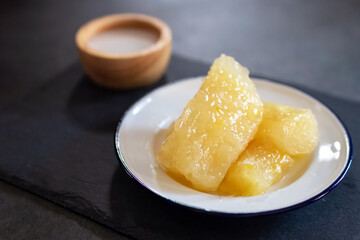 Cassava in syrup usually served coconut milk in vintage zinc coating dish on black stone background. Traditional desserts in Thailand.