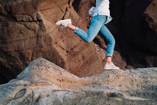 Low section of woman in casual wear running on rock