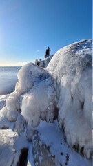 In the winter, the Baltic Sea and ice covered the frozen rocks at dawn. Baltic Sea - winter beach with frozen stones. The picturesque landscape of the Baltic Sea in the polar winter
