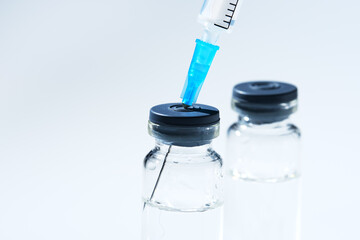 Close up glass vial with flu vaccine and syringe with needle. The concept of vaccination or...