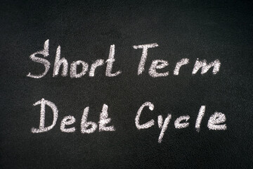 Chalk writing words Short Term Debt Cycle on blackboard.