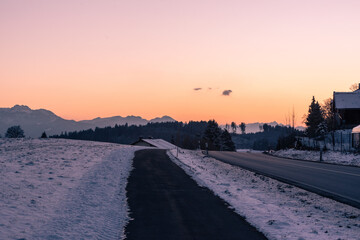 Sonnenuntergang bei Sondermoning in den Ostalpen im , Chiemgau mit Bergen, Schnee, und Wiese