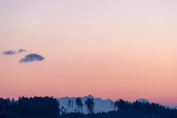 Sonnenuntergang bei Sondermoning in den Ostalpen im Chiemgau mit Bergenund Wald Silhouette